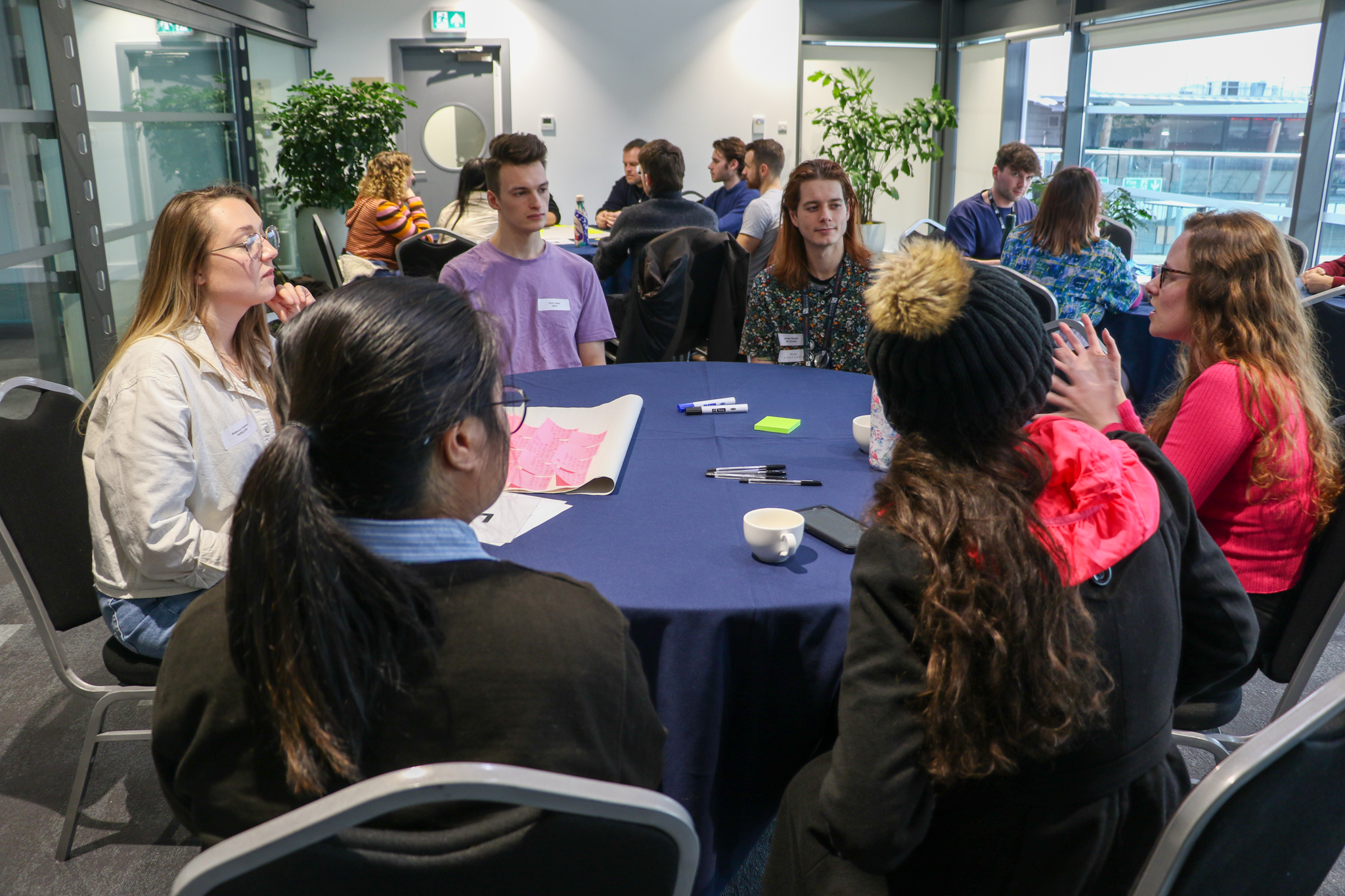 Students at World Café Knowledge Exchange event engaging in conversation around a round table