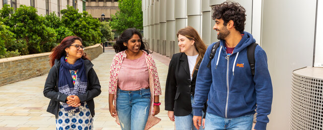 Group of four students walking around campus