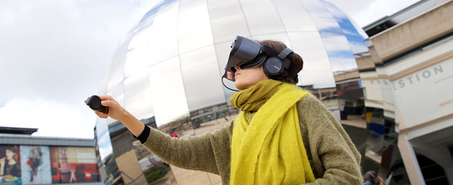 A student outside Bristol Planetarium in Millennium Square with a virtual reality headset on.