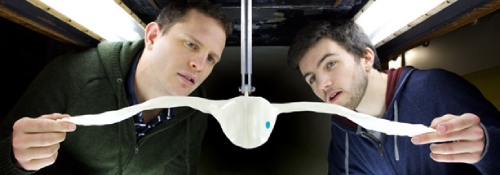 Two people testing a model bird in a wind tunnel.