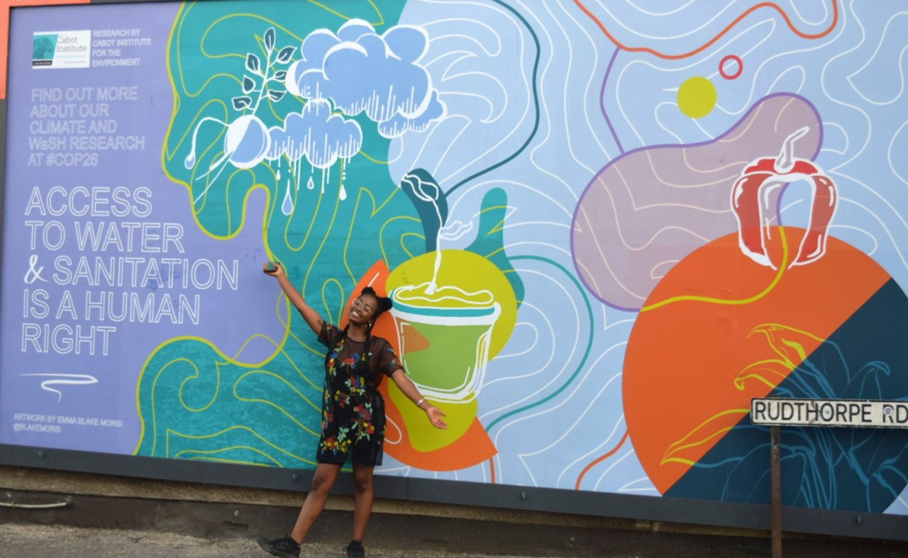 Image showing Emma Blake Morsi the artist in front of one of her billboards in Bristol entitled "Water and sanitation is a human right"