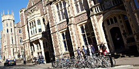 The outside of the Geographical Sciences building. There are groups of people standing and bikes parked nearby.