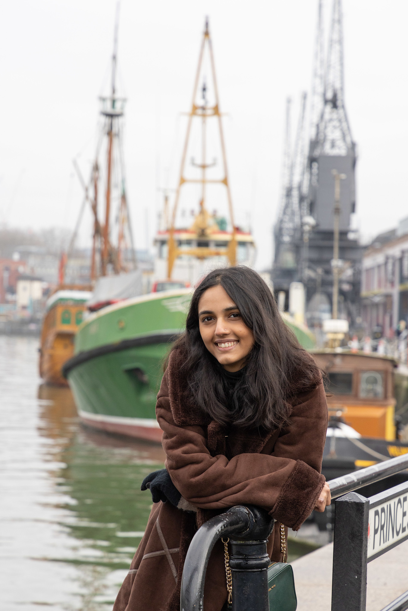 Female student smiling in front of a ship in Bristol Harbourside