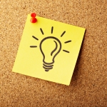 A lightbulb drawn on a post-it note pinned to a cork board.