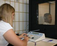 An audiologist conducting an audiometric hearing test in a sound-proof testing booth