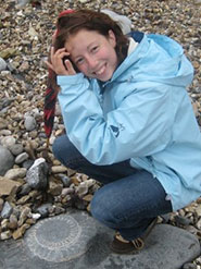 Liz Martin, the 250th student to have completed an MSc in Palaeobiology, with an ammonite fossil on the beach at Lyme Regis.