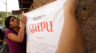 Image of people putting up a Quipu Project poster in Peru