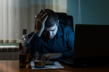 Generic image of a man feeling suicidal in front of a computer