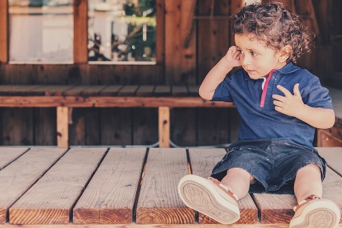 Image shows a young child pretending to hold a phone to his ear