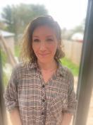 A woman with shoulder length brown hair wearing a checked shirt
