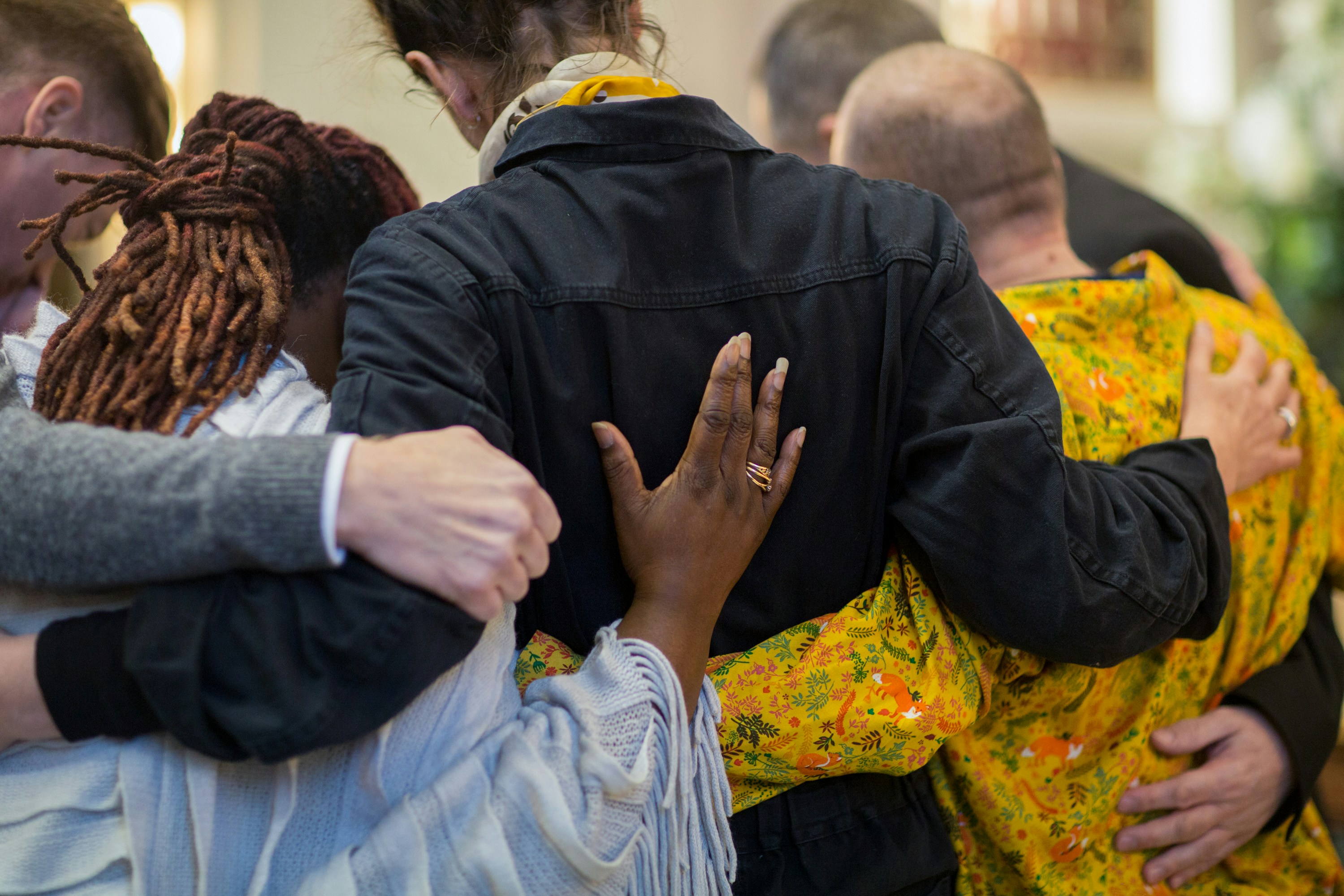 A group of people comfort each other at a funeral ceremony.