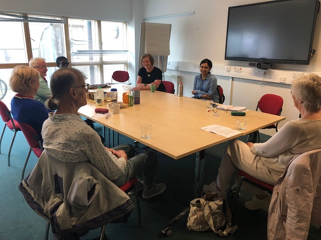 Members of the HAPPY Study PPI group sit around a table in a University teaching room chatting