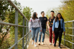 A group of students smiling walking across a bridge