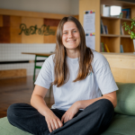 Image of Ella Lovibond sitting crossed legged on a green chair