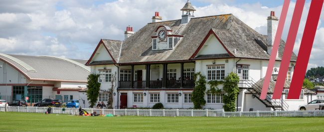 Image of the main pavilion at Coombe Dingle with the Sports Complex in the background. Image shows three lines, all shades of red, on the right hand side of the image.