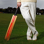 Person leaning on a cricket bat, wearing cricket whites, from the waist down. Links to Cricket club page on Bristol SU Website.