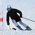 Downhill skier wearing a black jacket and a white helmet, skiing down a course. Links to Snowsports club page on Bristol SU Website.