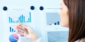 A woman pointing at a bar chart on a whiteboard.