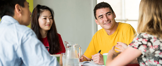 Four students in meeting around table with refeshments