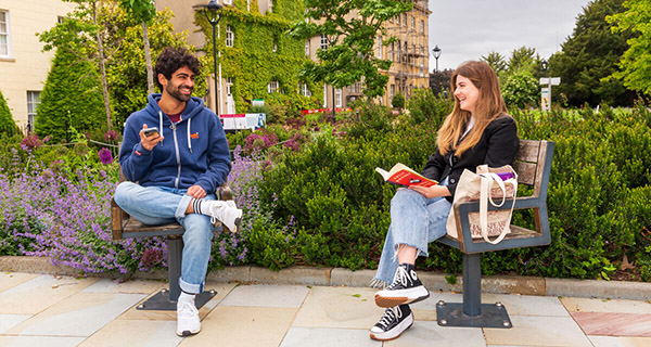 Two students chatting on ben in summer garden