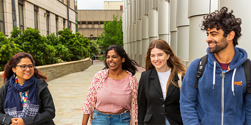 4 students walking and smiling on campus