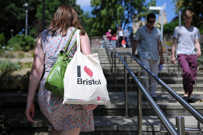 Students walking around the University campus during a visit. The student in focus is carrying a University tote bag that reads: I love Bristol. 