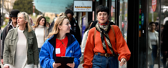 A prospective student walking and talking to a student ambassador with people behind them