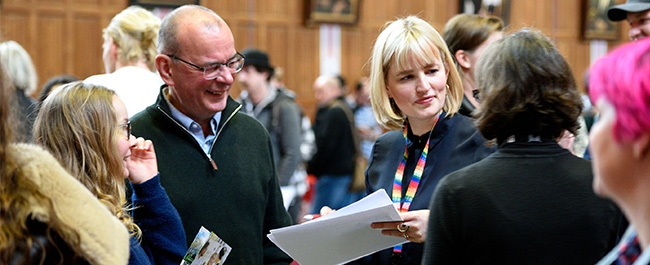 A university staff member talking to prospective student and their parent smiling