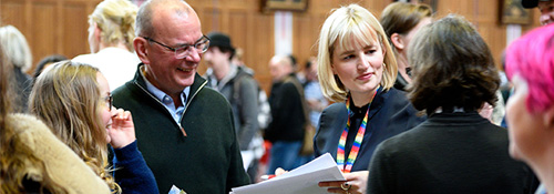 A university staff member talking to prospective student and their parent smiling