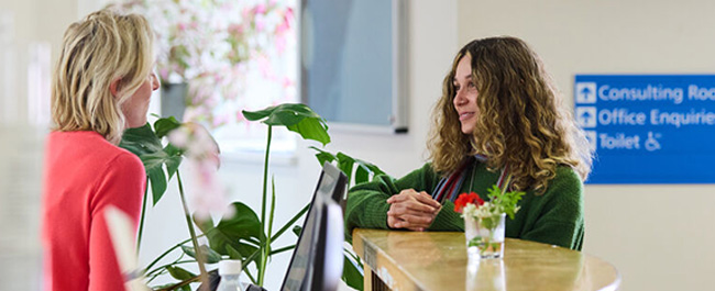 A female student speaking to a receptionist at the student heath service