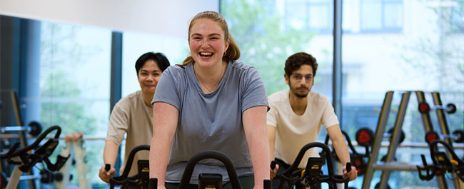 Three students on spin bikes smiling