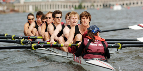 A group of Bristol students rowing along a river.