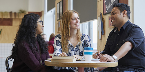Three students working together in a café.