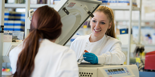 Two students working together with a piece of laboratory equipment.