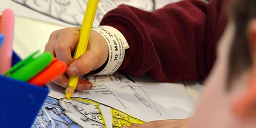 A close up of a child's hand colouring in a picture.