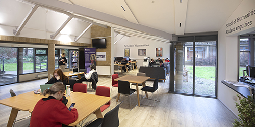 A sociable study space on campus with a number of students working independently throughout the room. 