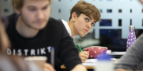 A student taking notes in a teaching room. 