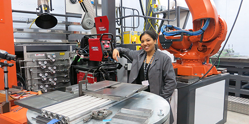 A student smiling while using a large piece of engineering equipment. 
