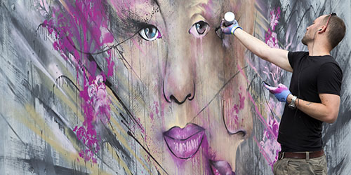 A person adds the finishing touches to a large mural. 