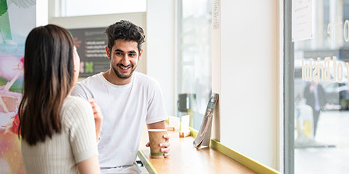 Two people sitting at a bar in a cafe.