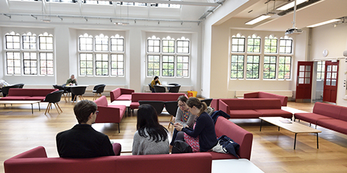 People sitting on sofas and at tables working in a communal space.