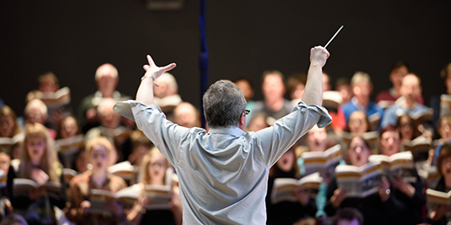 A person conducting a group of people singing.