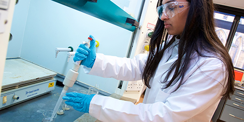 A person in protective scientific clothing working in a laboratory.