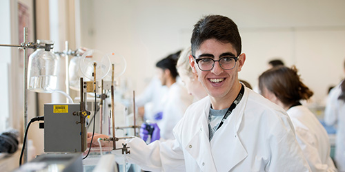 A person in a white lab coat working with scientific equipment.