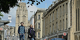 People walking on Park Street in Bristol. The Wills Memorial Building is at the top of the street in the background.