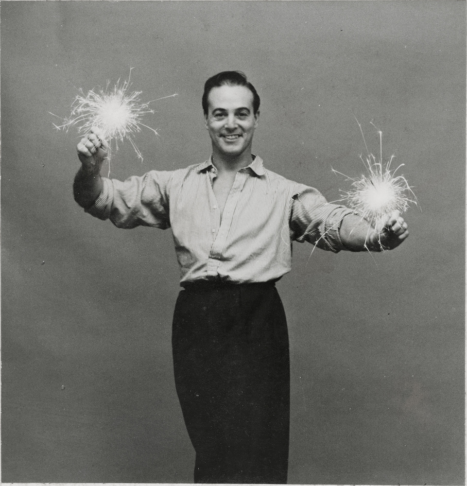 Oliver Messel holding a sparkler in each hand