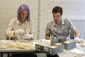 Two people wearing gloves and repackaging archives