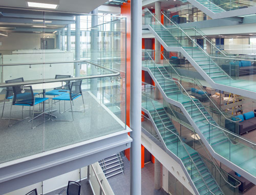 A multistory atrium with glass walls and visible seating areas and meeting rooms. 